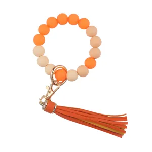 Silicone beaded keychain detail view, featuring orange and beige beads with leather tassel.