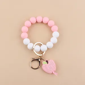Vista detallada del llavero pulsera de cuentas de silicona con colgante de manzana.