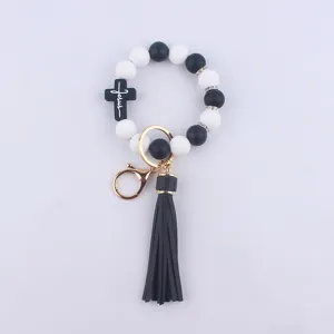 Black white silicone bead keychain wristlet with cross and leather tassel detail view.