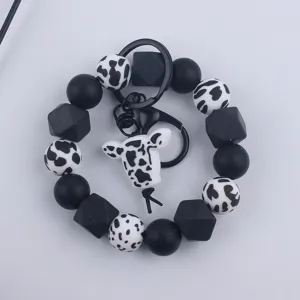 Black and white cow silicone bead keychain bracelet with cute animal pendant and metal ring.