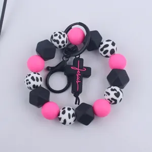 Silicone beaded wristlet keychain with cow print and cross pendant for keys and bags.
