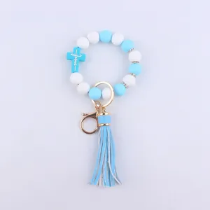 Close-up of blue white silicone bead cross keychain bracelet with leather tassel detail