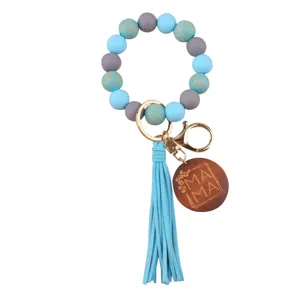 Silicone beaded wristlet keychain detail, featuring blue gray beads and wooden mama pendant.