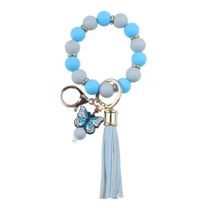 Silicone beaded wristlet keychain detail featuring a cute blue butterfly pendant and chic leather tassel.