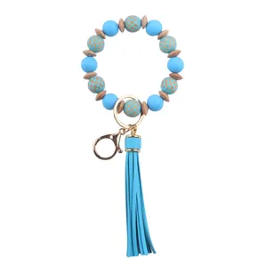 Llavero de pulsera de cuentas de silicona y madera azul con borla de cuero PU y anilla dorada.