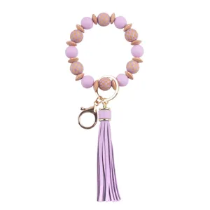 Llavero de pulsera de cuentas de silicona morada con borla de cuero PU y abalorios de madera.