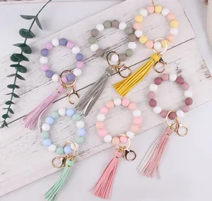 Silicone bead wristlet keychain bracelet with leather tassel and gold clasp details.