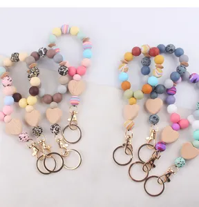 Silicone wrist keychain detail showing colorful beaded bracelet with wooden heart charm.