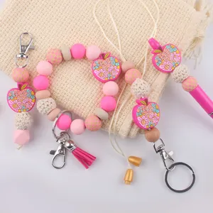 Silicone bead teacher keychain set detail view, featuring cute apple charms and pink wristlet.