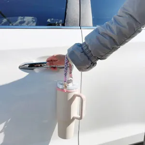Detailaufnahme eines bunten, handgeflochtenen Tassenriemens am Becher, stilvolle Alltagsszene.