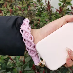 Detalle de correa de muñeca de macramé rosa hecha a mano, accesorio de cordón elegante.