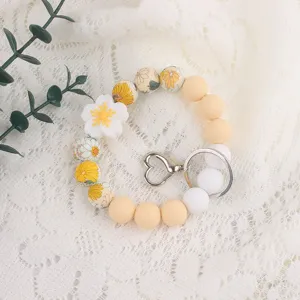 Detailed view of silicone bead keychain bracelet with flower charm and metal heart clasp.