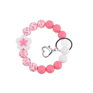 Silicone beaded wristlet keychain with flower charm, pink and white aesthetic accessories.