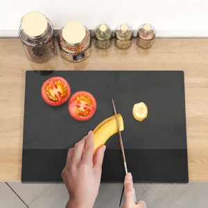 Modern black tempered glass cutting board for kitchen use showing sliced tomatoes