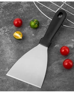 Detail of stainless steel spatula with black PP handle on a grey textured surface