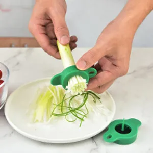 Action shot of a green manual scallion shredder tool being used to slice fresh green onions