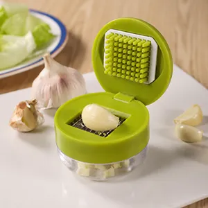 Close-up detail of a manual green garlic press featuring a stainless steel dicing grid