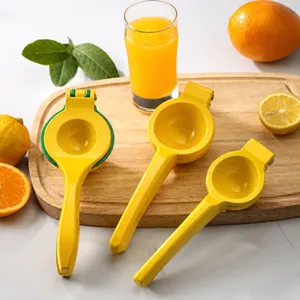Manual yellow stainless steel lemon squeezers on wooden board with orange juice