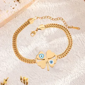 Primer plano detallado de la pulsera de trébol de titanio dorado con ojo turco azul.