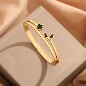 Pulsera rígida doble de acero inoxidable dorado con dije de flor y mariposa negra elegante.