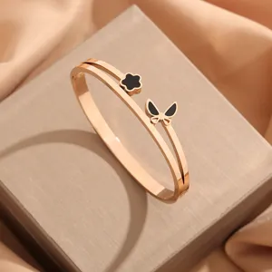 Brazalete abierto doble de acero de titanio oro rosa con flor negra y mariposa.