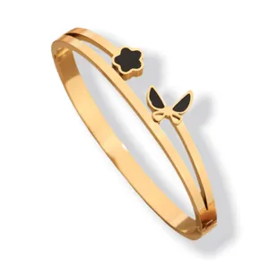 Brazalete abierto de acero inoxidable dorado con flor negra y elegante dije de mariposa.