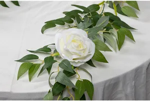 Nahaufnahme künstliche weiße Rosenranke mit grünen Blättern für Tischdeko und Hochzeit.
