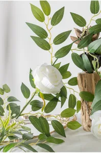 Nahaufnahme Detail von künstlicher weißer Rosenrebe mit grünen Blättern für die Dekoration.