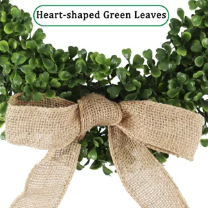 Couronne de feuilles vertes artificielles avec nœud en jute pour la déco de porte.