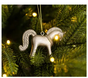 Detailaufnahme eines silbernen Pferd Weihnachtsbaumschmucks hängend an festlichen grünen Zweigen.