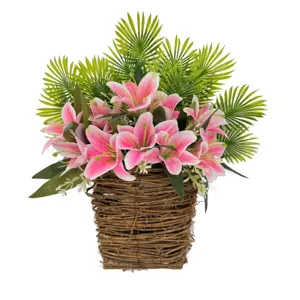 Artificial pink lily flowers with green palm leaves detail in wicker basket for home decor.