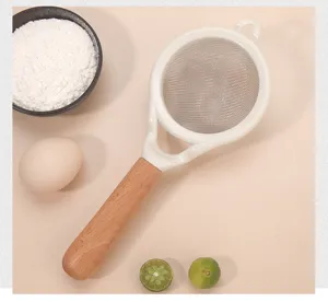 Vue détaillée du tamis à farine en acier inoxydable avec maille fine et manche en bois.