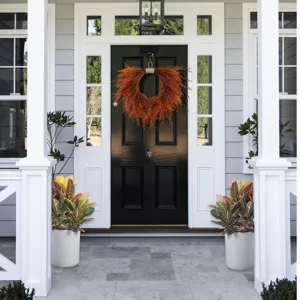 Detailed view of artificial autumn fern wreath hanging on front door for home decor scene.