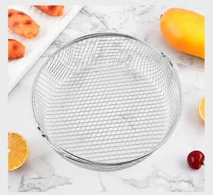 Detailed view of a stainless steel air fryer mesh basket with handle on marble.