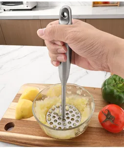 Détail du presse-purée en pommes de terre en acier inoxydable dans un bol en verre