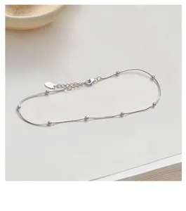 Silver snake chain anklet with delicate beads, elegant minimalist foot jewelry for women.