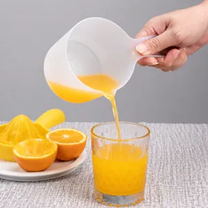 Handheld plastic measuring cup with scale for kitchen juice pouring and manual juicer set.
