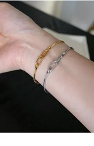 Nahaufnahme von goldenen und silbernen Schlangenketten-Armbändern am Handgelenk getragen.