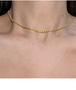 Gedetailleerde close-up van een delicate vergulde zilveren getwiste ketting om de nek.