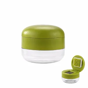 Compact manual garlic chopper with clear container and green press lid for kitchen use.