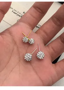 Detaillierte Nahaufnahme von glitzernden Kristallkugel-Ohrsteckern in der Hand, eleganter Schmuck.
