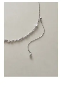 Close-up detail of silver braided chain necklace with adjustable sliding bead and tassel.