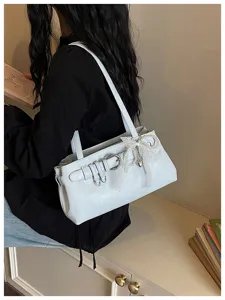 Détail de sac porté épaule blanc, avec boucle en métal et pendentif en perles et dentelle.