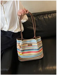 Detail van kleurrijke geweven shopper tas met bruine lederen handgrepen en schattige bloemenhanger.