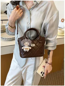 Gros plan détaillé du sac à bandoulière matelassé rétro avec joli pendentif poupée chic.
