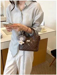 Élégant sac seau matelassé rétro en cuir bandoulière pour femme avec charm poupée.