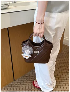 Vue détaillée d'un sac seau matelassé marron chic avec un joli charm poupée, style élégant.