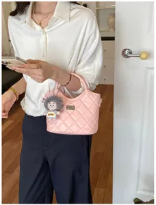 Élégant sac seau matelassé rose avec fermoir en métal et charmant pendentif poupée en peluche.