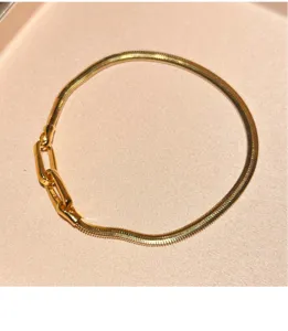 Detailed close-up of the shiny snake chain bracelet featuring a unique metal link clasp.