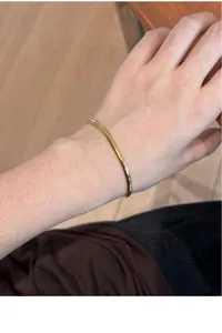 Gold herringbone chain bracelet detail shot, elegant flexible wrist jewelry for daily wear.
